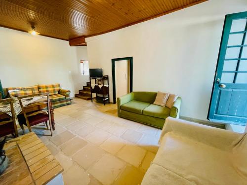 a living room with a green couch and a table at 1908 - live a century back in Paliámpela
