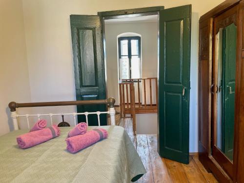 a bedroom with a bed with pink pillows on it at 1908 - live a century back in Paliámpela