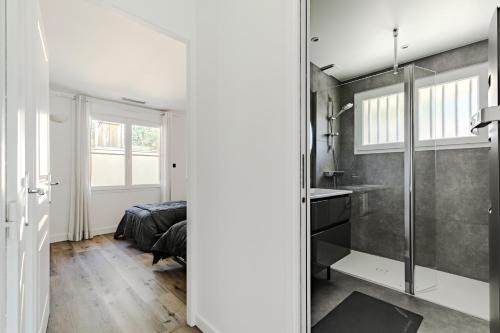 Cette chambre comprend un lit et une salle de bains pourvue d'une douche. dans l'établissement Villa rénovée,piscine chauffée, dans les pins à 4min de l'océan-AG29, à Lacanau