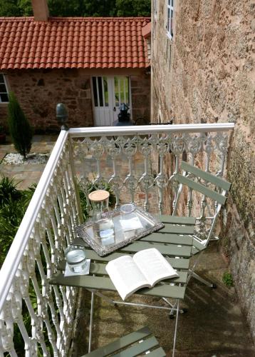 a table on a balcony with a book at Hotel Pazo de Bieite in Boimorto