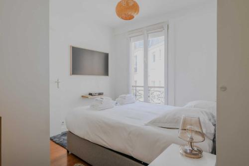 une chambre blanche avec un grand lit et une fenêtre dans l'établissement Peaceful apartment - 1BD- 4P - Montmartre, à Paris