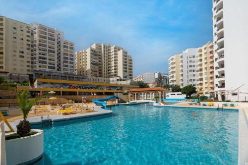 a large swimming pool in a city with tall buildings at Casa3_Praia_Beach_House in Portimão