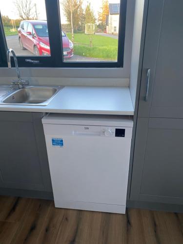 a small kitchen with a sink and a window at Killyfole lakeside lodges in Corranny