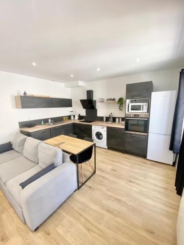 un salon avec un canapé blanc et une cuisine dans l'établissement Le Lumos - Chaleureux & Calme, à Riom