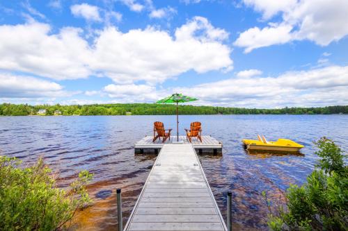 a dock with two chairs and an umbrella on a lake at Lake House Chalet Laurentians in Nominingue