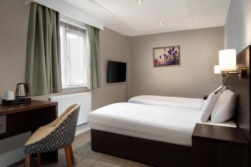 a hotel room with a bed and a desk and a chair at Trafford Hall Hotel Manchester, Trademark Collection by Wyndham in Manchester