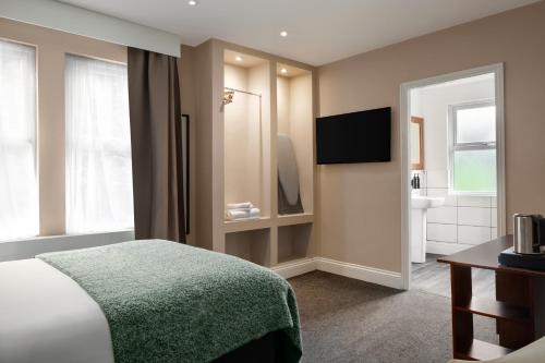 a hotel room with a bed and a bathroom at Trafford Hall Hotel Manchester, Trademark Collection by Wyndham in Manchester