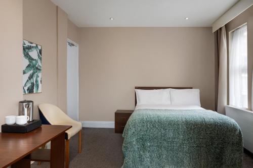 a bedroom with a bed and a desk and a window at Trafford Hall Hotel Manchester, Trademark Collection by Wyndham in Manchester