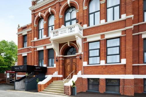 a red brick building with stairs in front of it at Trafford Hall Hotel Manchester, Trademark Collection by Wyndham in Manchester