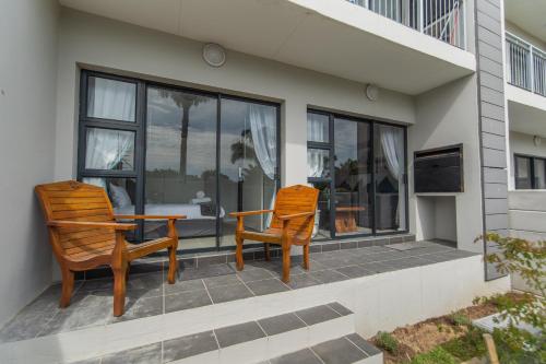 two chairs and a table on a patio with windows at Jetsetter's Retreat Apartment in Hallack Rock