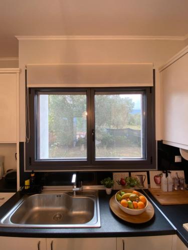 a kitchen with two windows and a bowl of fruit on the counter at Dimis cozy villa near the sea! in Litochoro