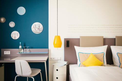 a bedroom with a bed and a desk and a chair at Vienna House Easy by Wyndham Landsberg in Landsberg am Lech