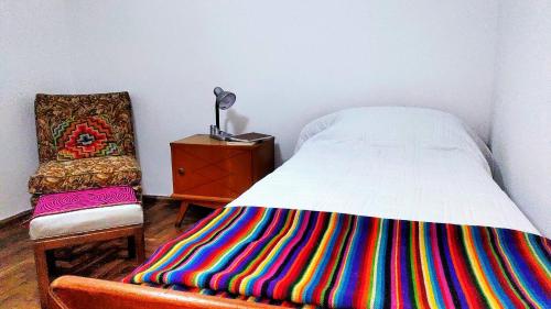a bed with a colorful blanket next to a chair at Habitación silenciosa Nº2 en Dpto Compartido in Cordoba