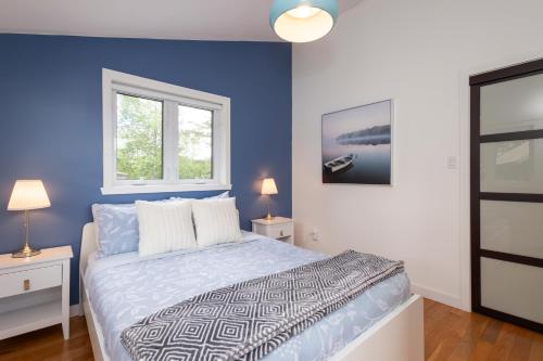 a blue bedroom with a bed and two windows at Lake House Chalet Laurentians in Nominingue