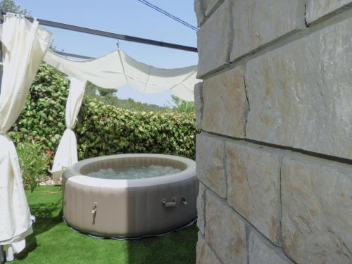 a hot tub in the grass next to a stone wall at Apartments IVO in Stomorska
