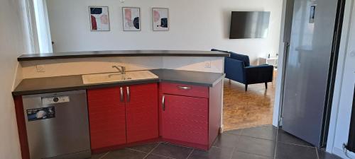 une cuisine avec un évier et des armoires rouges et un salon dans l'établissement Charmante maison proche Futuroscope CHU Centre ville, à Buxerolles