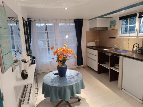 une cuisine avec une table avec un vase de fleurs dessus dans l'établissement La chaumière, à Rambouillet
