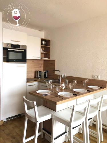 - une cuisine avec une table, des chaises blanches et un évier dans l'établissement Le Mailheul - Tout compris - vue mer - 160 m de la plage, à Narbonne-Plage