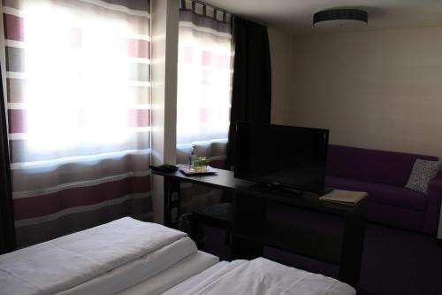 a hotel room with a bed and a television on a desk at Amiga Hotel München Messe in Munich