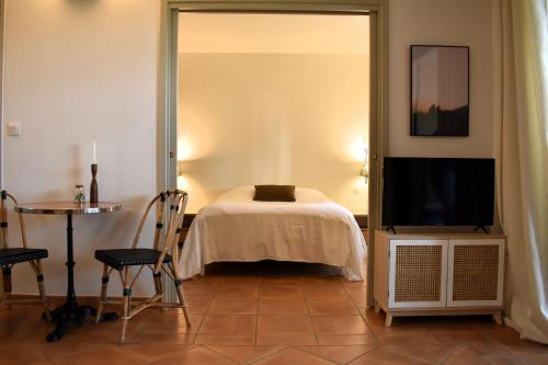 une chambre avec un lit, une télévision et une table dans l'établissement Gîte Confortable Vue Exceptionnelle - Golf de Saumane, à Saumane-de-Vaucluse
