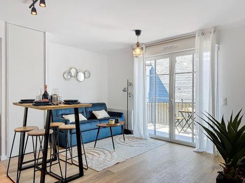 un salon avec une table et un canapé bleu dans l'établissement Opale YourHostHelper, à Deauville