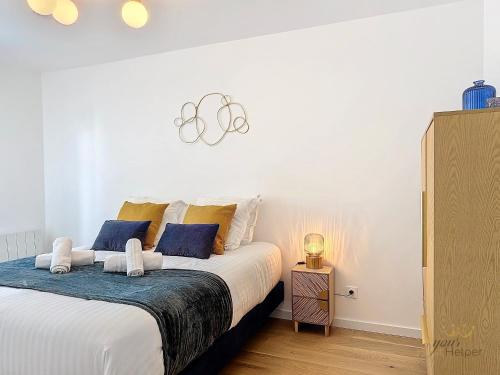 - une chambre dotée d'un grand lit avec des oreillers bleus et jaunes dans l'établissement Opale YourHostHelper, à Deauville