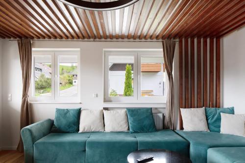 a living room with a blue couch and two windows at Skylodges in Oberried