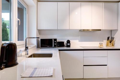 a white kitchen with a sink and a microwave at Skylodges in Oberried