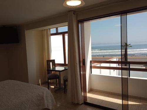 a bedroom with a bed and a view of the beach at Hotel Huankarute in Huanchaco