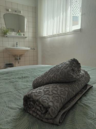 ヴェーツェにあるGuesthouse - Weeze Roomsのシンク付きのベッドの上に置かれた2枚の毛布