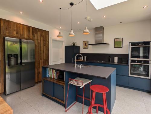 a kitchen with blue cabinets and a counter with a red stool at Bright, modern home in South Belfast in Belfast