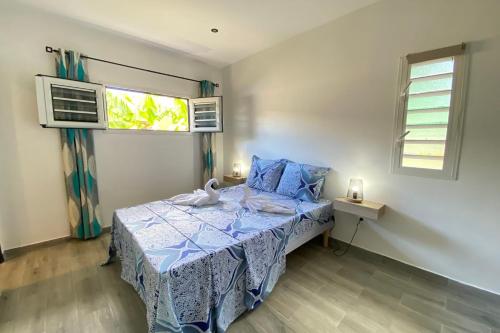 a small bedroom with a bed and two windows at 972M Beautiful air-conditioned villa with garden in Le Carbet