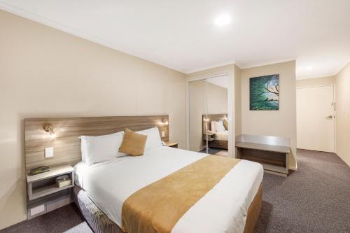 a hotel room with a large bed and a desk at Ciloms Airport Lodge Melbourne Airport in Melbourne