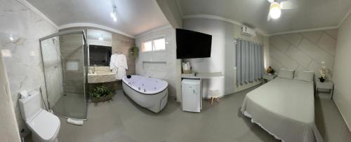 a large white bathroom with a bed and a bath tub at Pousada Praia Grande in Ubatuba