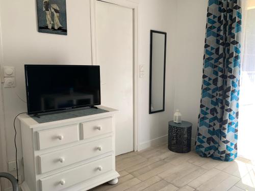 eine weiße Kommode mit einem Fernseher darüber in der Unterkunft La Grande Terrasse, appartement rez-de-jardin in Caen