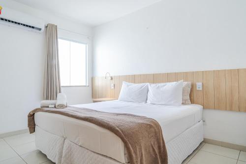 a bedroom with a large white bed with a window at Pousada Areia do Forte in Cabo Frio