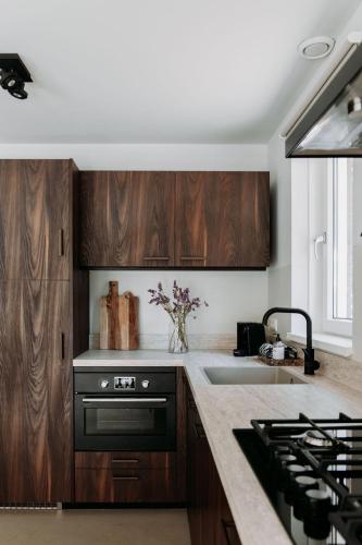 a kitchen with wooden cabinets and a black oven at Foss Lodge - luxe boutique boshuis Veluwe in Nunspeet