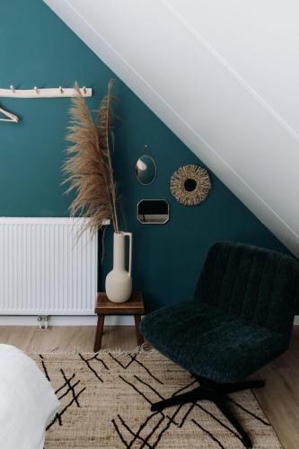 a green chair in a room with a blue wall at Foss Lodge - luxe boutique boshuis Veluwe in Nunspeet