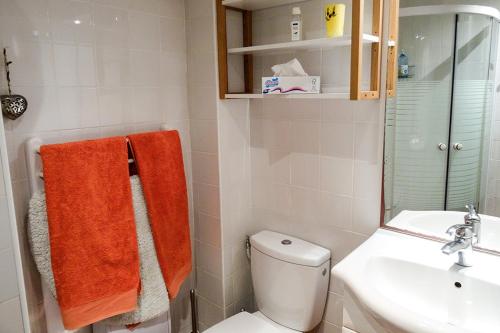 La salle de bains est pourvue de toilettes, d'un lavabo et de serviettes orange. dans l'établissement La vie de château à Orgeval - Chambre Feydeau, à Orgeval