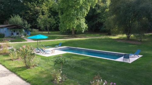 une cour avec une piscine et un parasol dans l'établissement La vie de château à Orgeval - Chambre Feydeau, à Orgeval