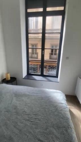 - une chambre avec une fenêtre donnant sur un bâtiment dans l'établissement Cosy City Center Suite, à Saint-Étienne