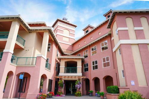 a large pink building with flowers in the courtyard at Borgata Lodge Resort in Kelowna