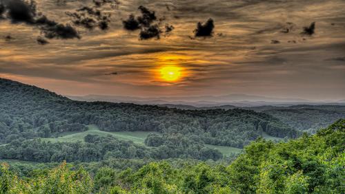 a sunset over a valley with trees and mountains at An Owl's Perch in Morganton