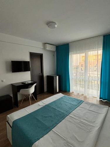 a bedroom with a large bed with a desk and blue curtains at Vila Sofia in Eforie Nord