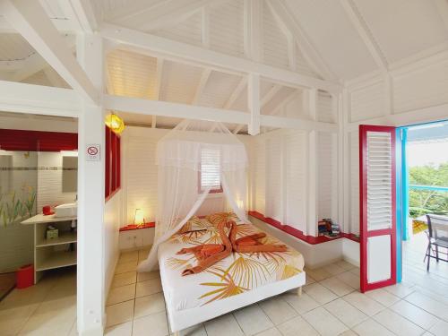 Un dormitorio con una cama blanca con dosel. en Pipirite Chantant - Studios Vue Mer, en Sainte-Rose