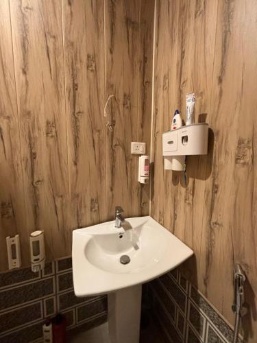 a bathroom with a white sink and a wooden wall at OMAR KHAYYAM HOUSEBOAT RETREAT and FAVELA HEADROOMS in Srinagar