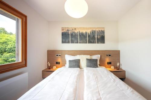 a bedroom with a large white bed with a window at Chalet Les Genêts, vue imprenable sur le lac in Gérardmer