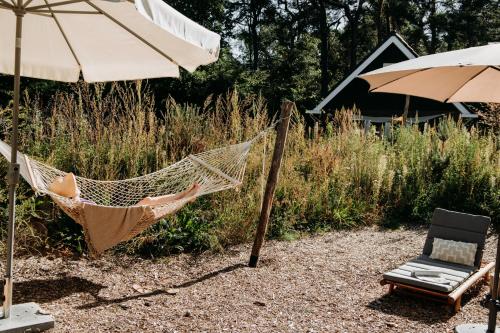 a hammock and a chair and an umbrella at Foss Lodge - luxe boutique boshuis Veluwe in Nunspeet