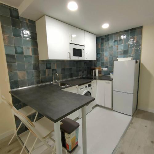 a kitchen with a table and a white refrigerator at Apartamentos Megaleon in Segovia