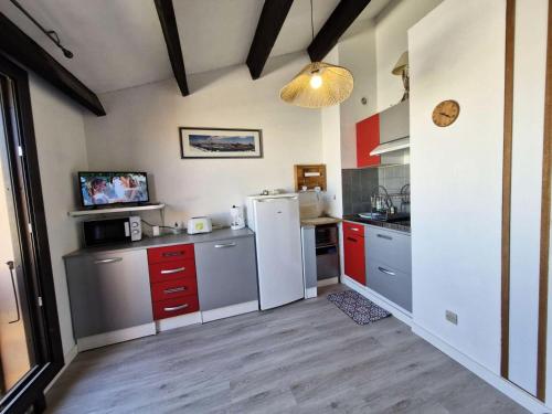 La cuisine est équipée d'un réfrigérateur blanc et de placards rouges. dans l'établissement Résidence Le Castellet - 2 Pièces pour 4 Personnes 501, à Leucate